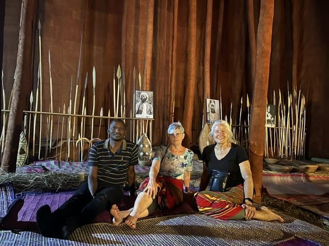 Guests enjoying a cultural experience among traditional spears and barkcloth