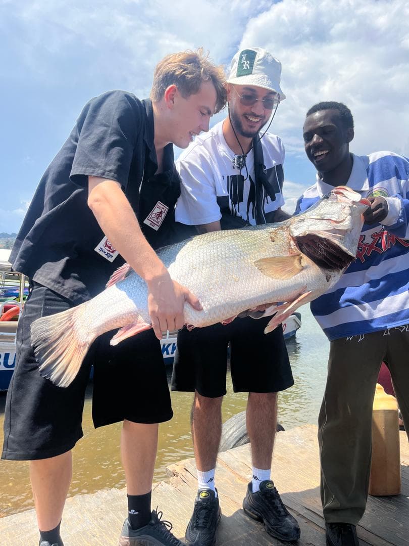 Travelers holding up a freshly caught Nile perch